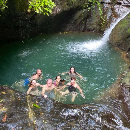 Family swimming in a natural pool at Ebano Waterfall