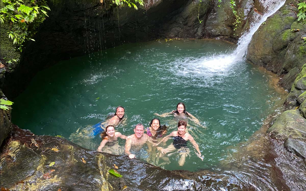 Family swimming in a natural pool at Ebano Waterfall